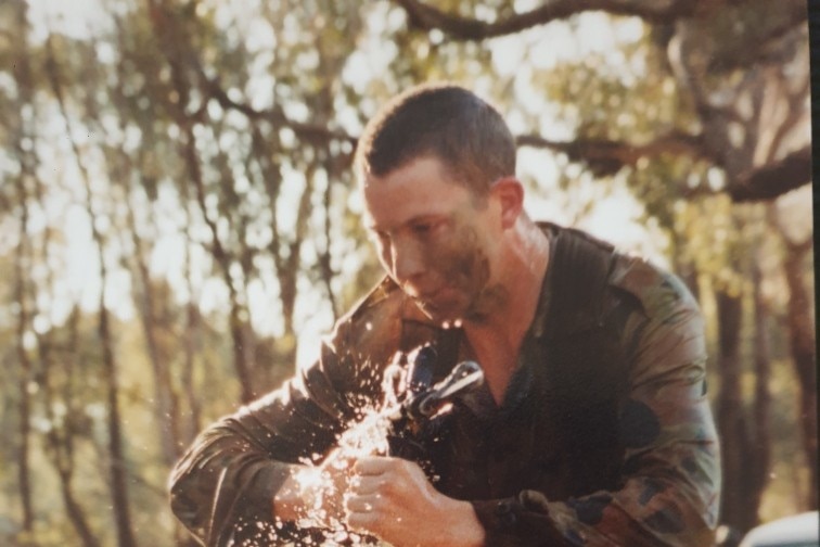 Wodonga veteran Eli Turner holding gun and wading through water during training exercise at Kapooka in 2001.