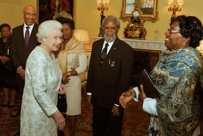 the wheen in silver smiles in a palace reception room informally greeting commonwealth guests