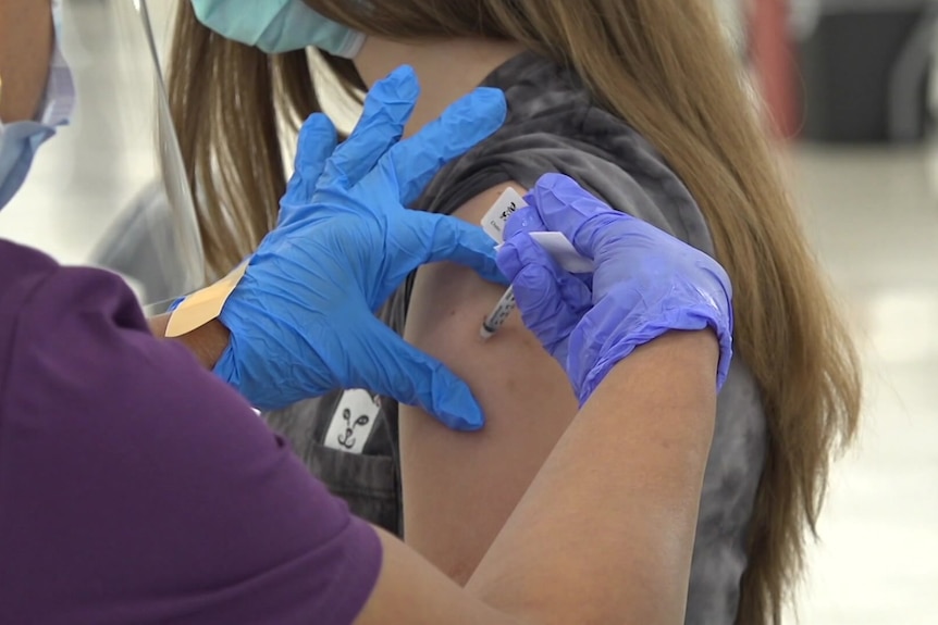 A girl is given a needle in her left arm.