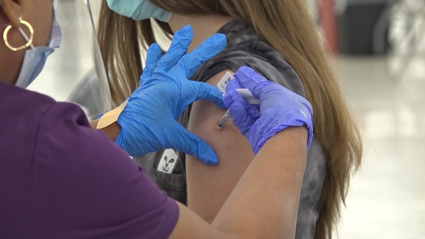 A girl is given a needle in her left arm.