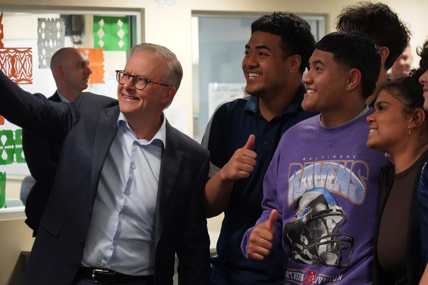 Prime Minister Anthony Albanese takes a selfie with a group of teenagers.