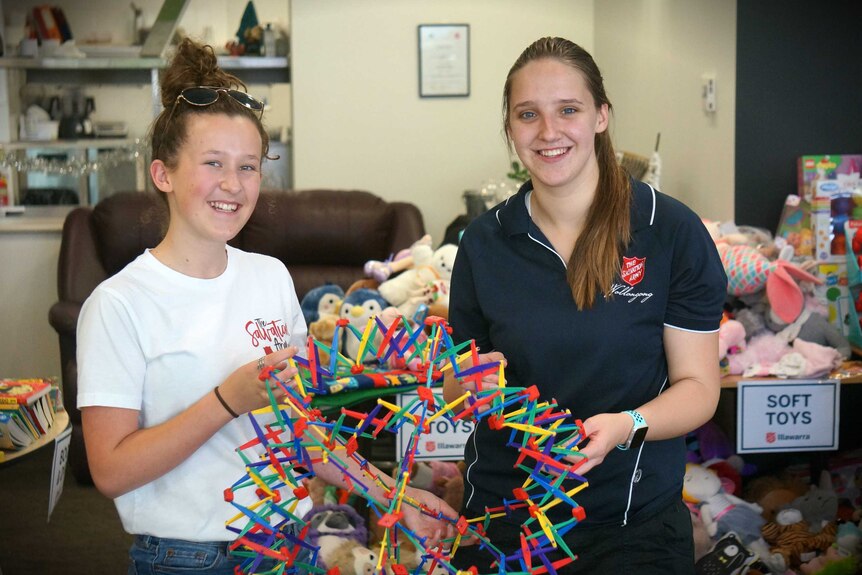 Young volunteers stand with a large toy.