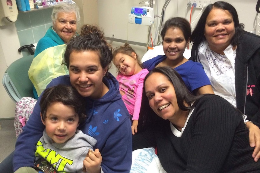 Family sitting on a hospital bed smiling at the camera