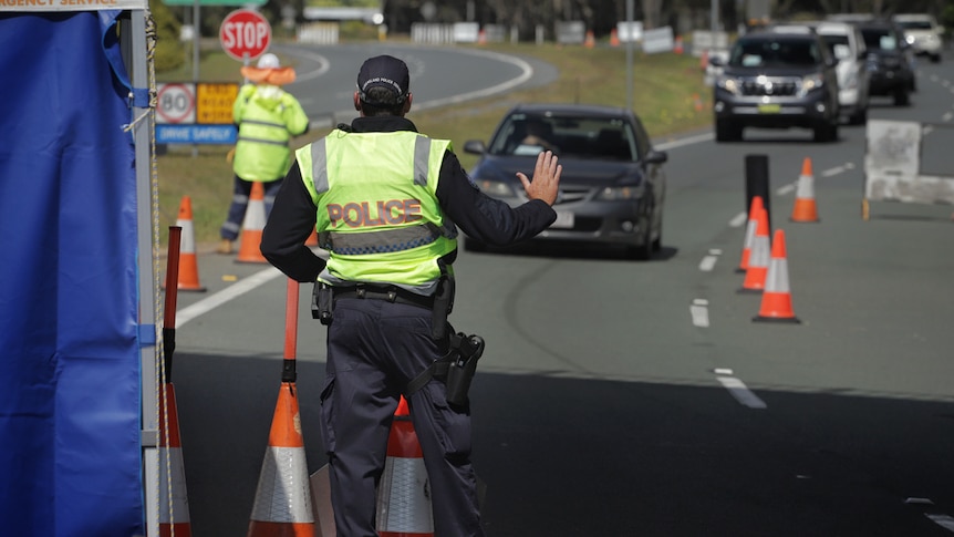 A police officer stops a car at the Queensland border checkpoint on the Gold Coast Highway at Bilinga on August 26, 2020.