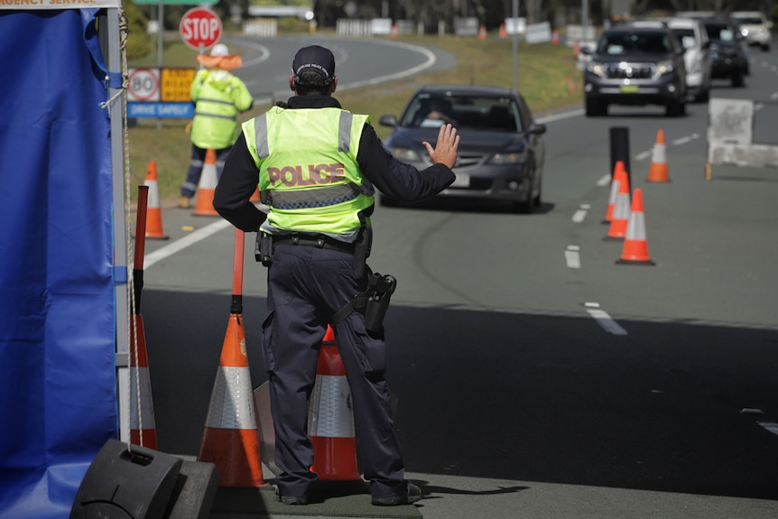 A police officer stops a car at the Queensland border checkpoint on the Gold Coast Highway at Bilinga on August 26, 2020.