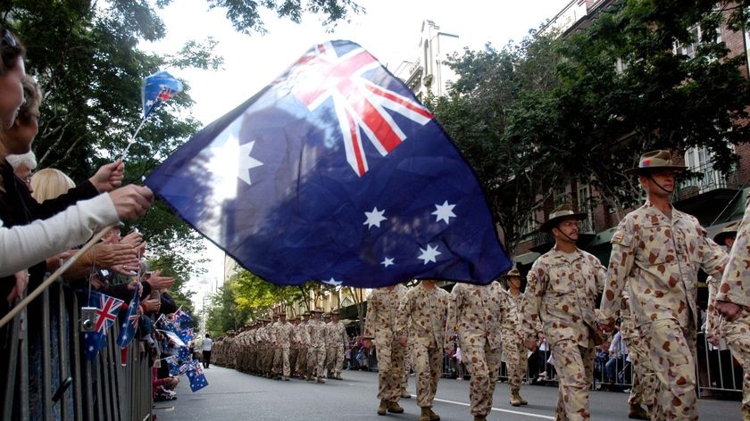 A member of the crowd waves an Australian flag during an Anzac Day march