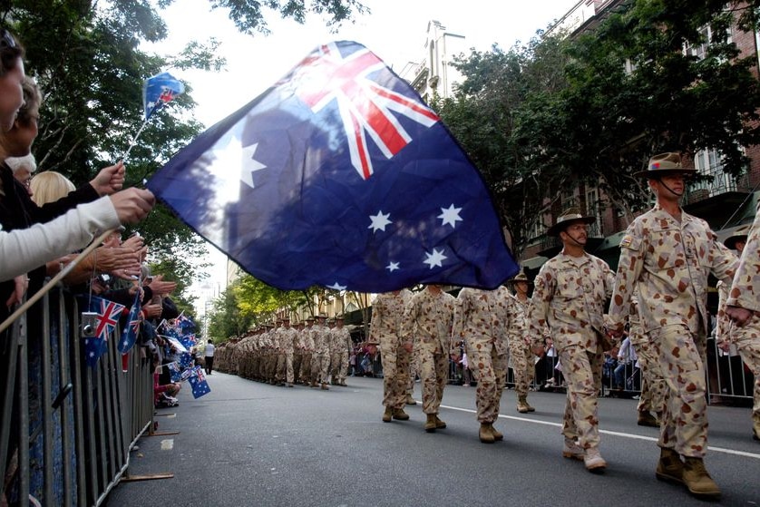 A member of the crowd waves an Australian flag during an Anzac Day march