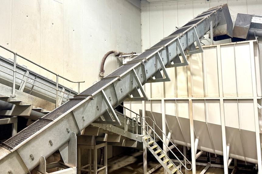 Inside a factory with a closed conveyor belt and big vat.