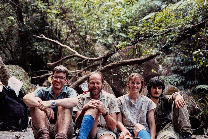 A file photo from 1982 of three men and one woman sitting in the rainforest.
