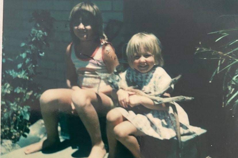 two barefoot girls sit on pavers in an old, sepia-toned photograph