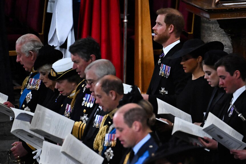 Britain's Prince Harry and Meghan Markle stand amongst guests at the Queen's funeral. 