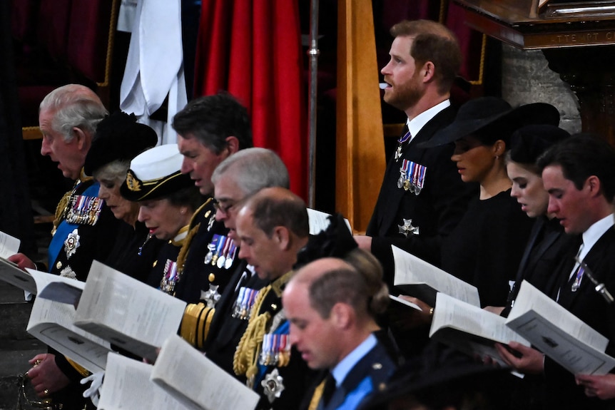 Britain's Prince Harry and Meghan Markle stand amongst guests at the Queen's funeral. 