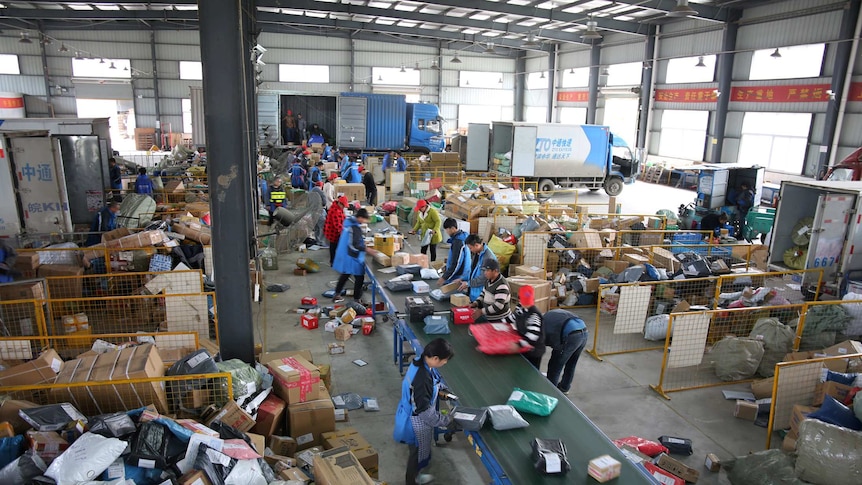 Workers pack boxes in a warehouse.