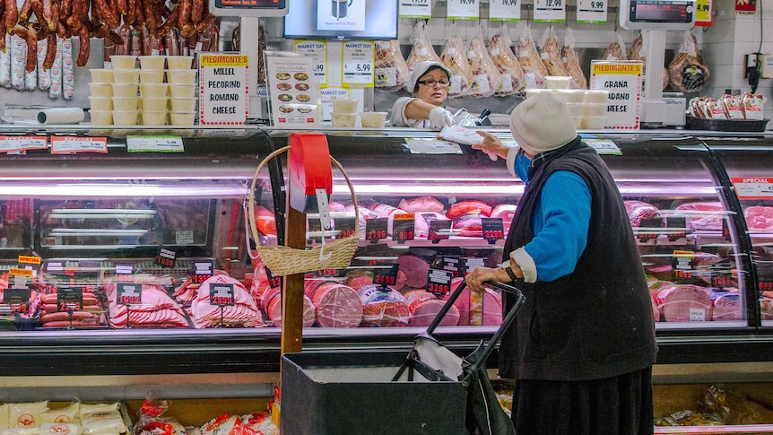 A regular customer pushing a leather shopping trolley is served at the delicatessen.