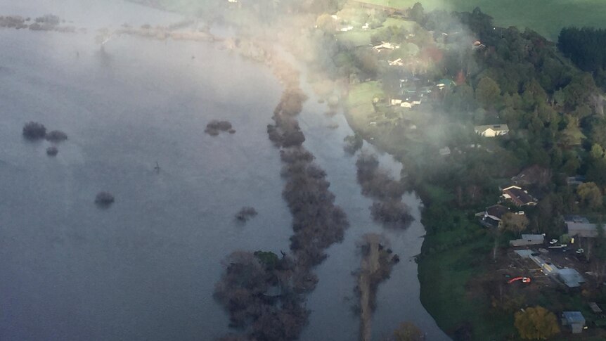 Aerial view of the flooded South Esk River close to homes and with trees sticking out of the water.