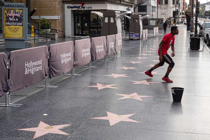 A man dances on an empty street that is usually teeming with people but is empty due to coronavirus fears.