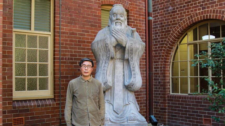 Senior Lecturer Xiaohuan Zhao at the University of Sydney in front of a statue of Confucius