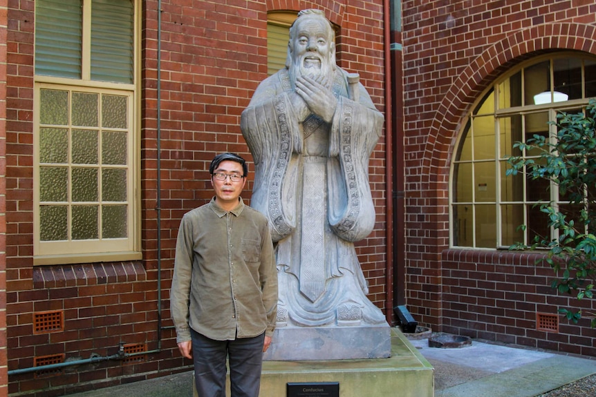 Senior Lecturer Xiaohuan Zhao at the University of Sydney in front of a statue of Confucius