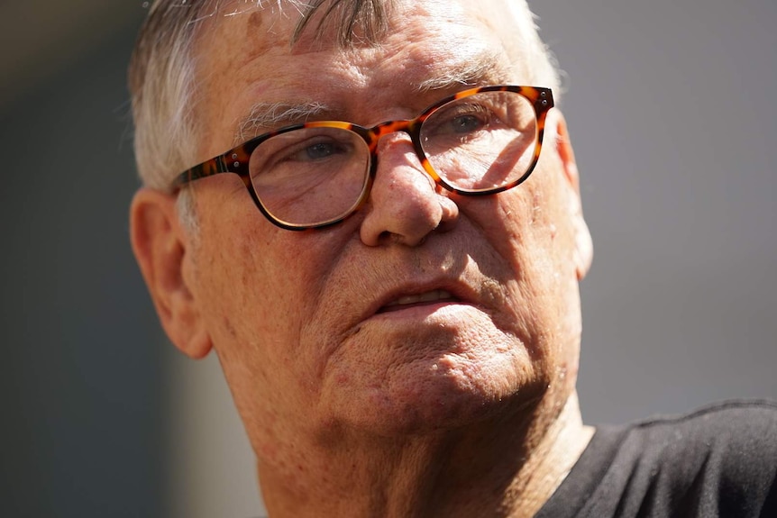 A headshot of a man with glasses and a grey t-shirt.