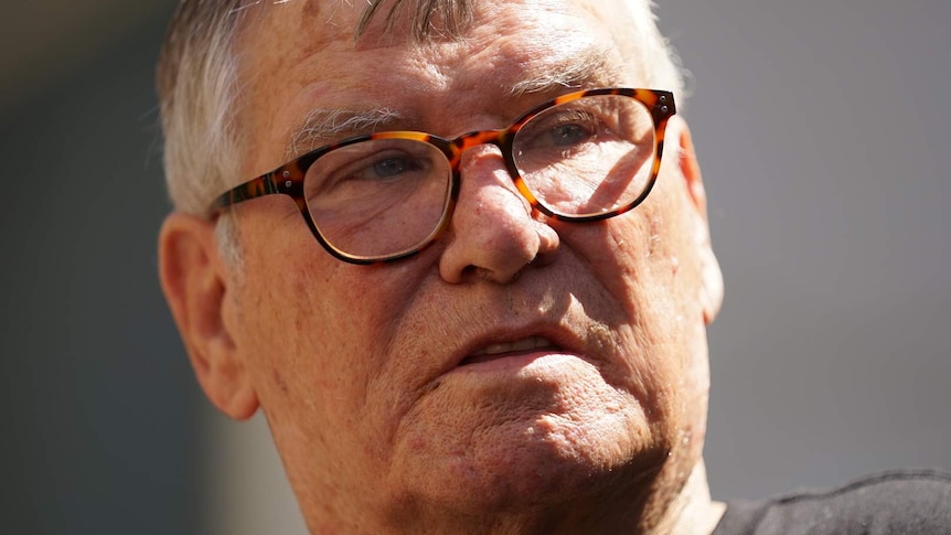 A headshot of a man with glasses and a grey t-shirt.