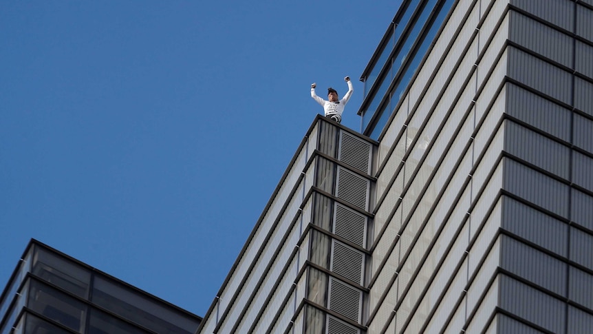 man raised arms at the top of a building