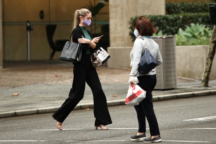 Woman with mauve COVID mask walking through Perth CBD.