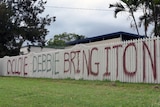 A fence spraypainted with the words 'Cyclone Debbie bring it on'