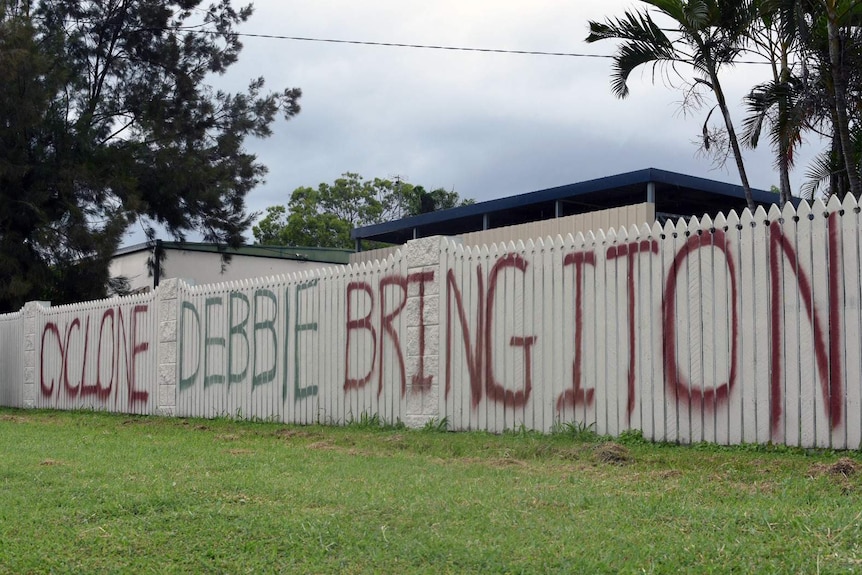 A fence spraypainted with the words 'Cyclone Debbie bring it on'