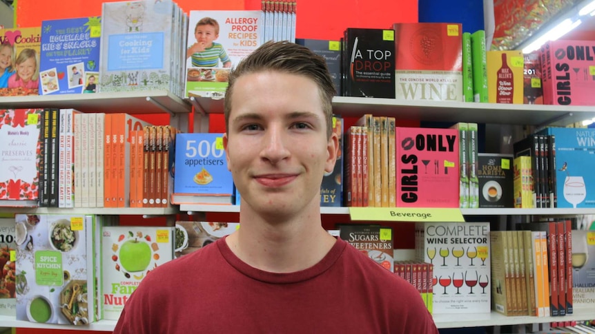 A young man in front of a book shelf.