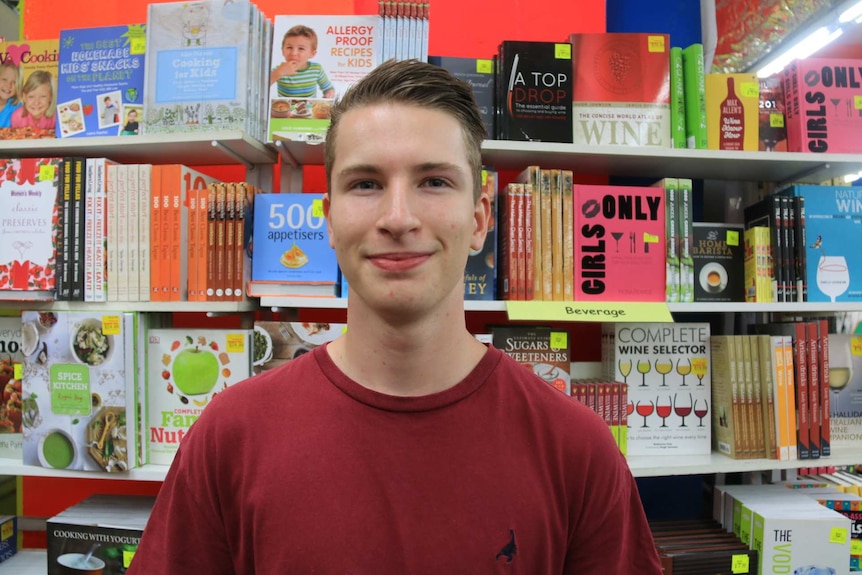 A young man in front of a book shelf.