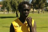 Teenager Kuol Akut, standing in a park with his sporting jersey, fell into a coma after collapsing outside a party in Girrawheen