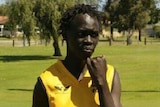 Teenager Kuol Atuk, standing in a park with his sporting jersey, died after falling into a coma at a party in Girrawheen.