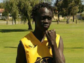 Teenager Kuol Atuk, standing in a park with his sporting jersey, fell into a coma after collapsing outside a party in Girrawheen
