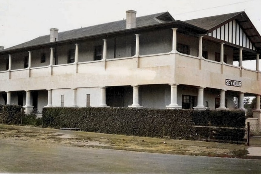 A large two story building with upstairs wraparound balcony 