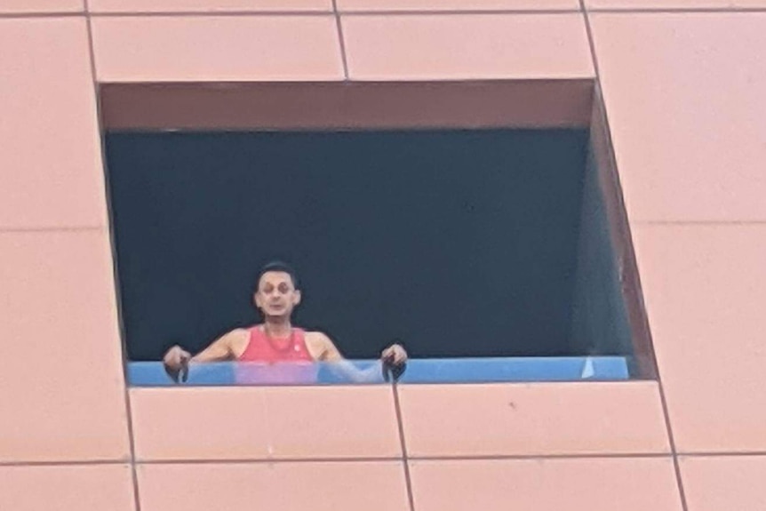 A man looking down from a balcony of a tall building