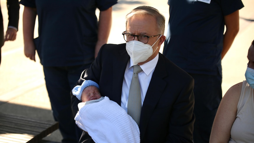 anthony albanese holds a baby why campaigning in a face mask