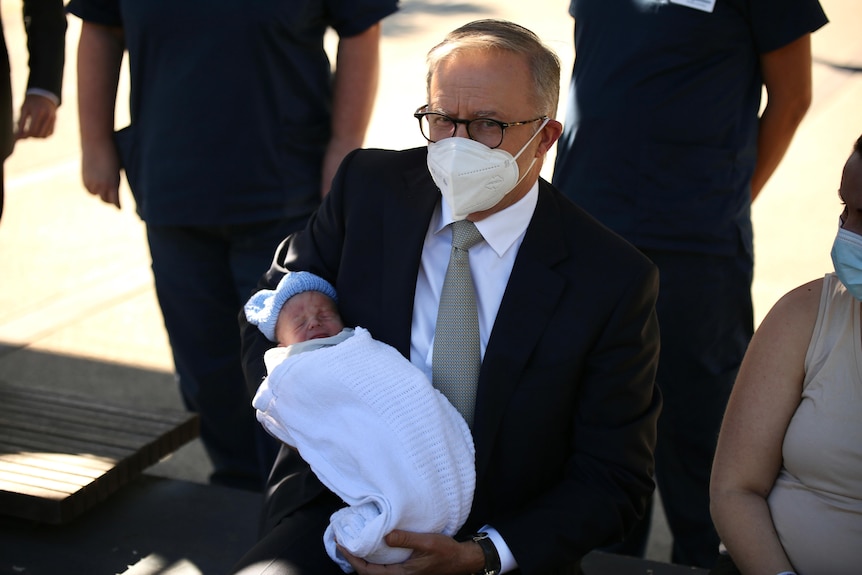 anthony albanese holds a baby why campaigning in a face mask