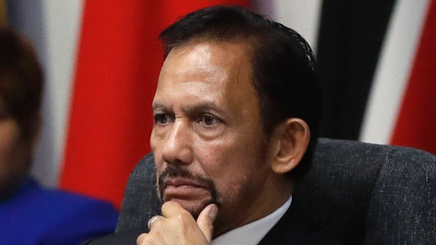 Brunei's sultan looks stern and holds his chin.