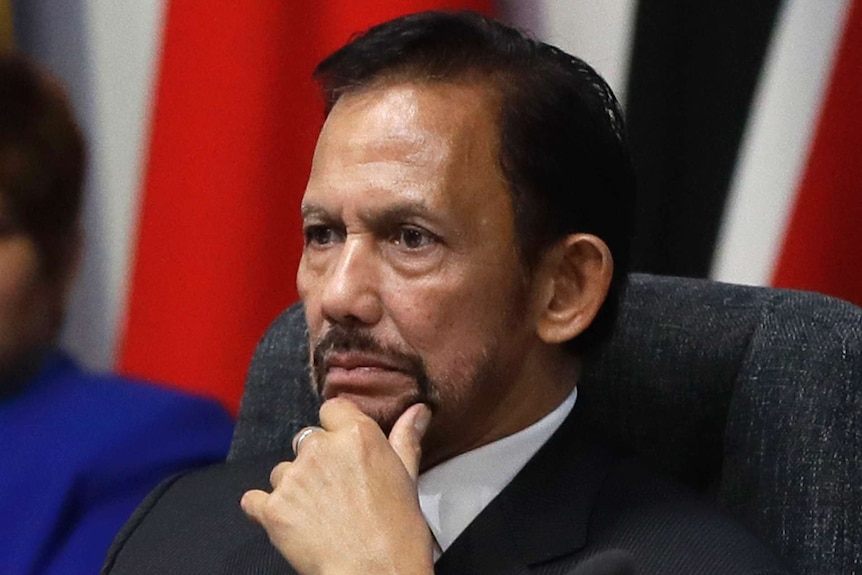 Brunei's sultan looks stern and holds his chin in a close-up photo.