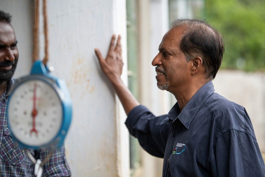 Amal Suriyage speaks with his farm manager, next to a weighing machine.