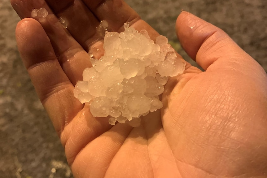 A hand holding a large cluster of hail stones