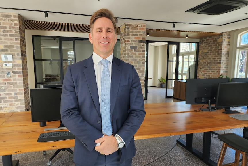 A man stands in a suit in an office. 