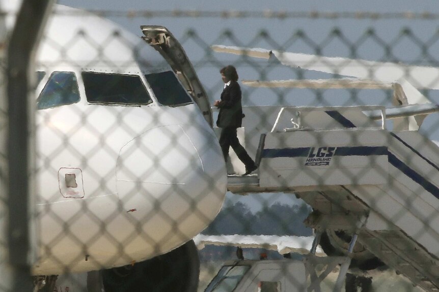 A person wearing a uniform walks onto a plane