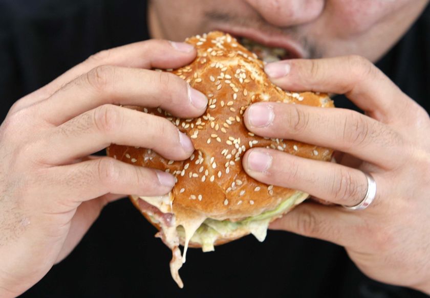 A person takes a bite from a hamburger