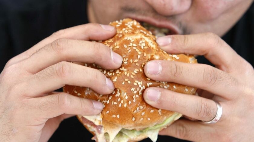 A person takes a bite from a hamburger