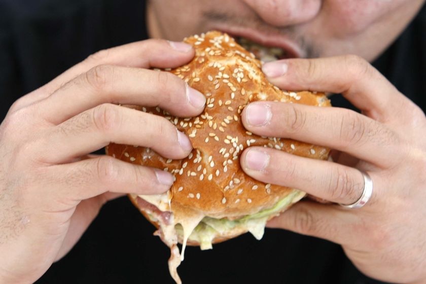 A person takes a bite from a hamburger