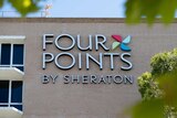 The exterior of the Four Points Sheraton in Perth with a large sign on a brick wall.