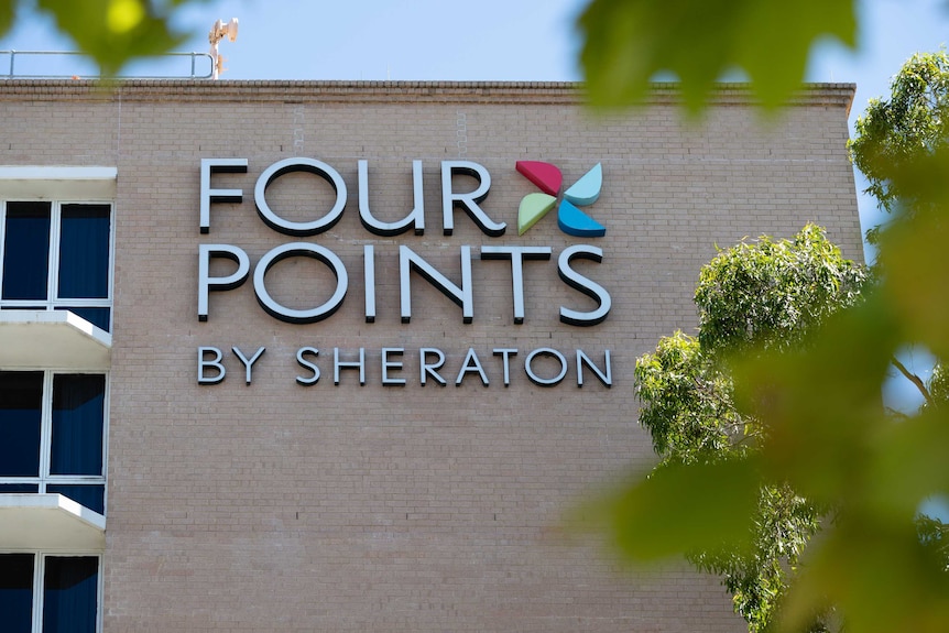 The exterior of the Four Points Sheraton in Perth with a large sign on a brick wall.