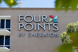 The exterior of the Four Points Sheraton in Perth with a large sign on a brick wall.