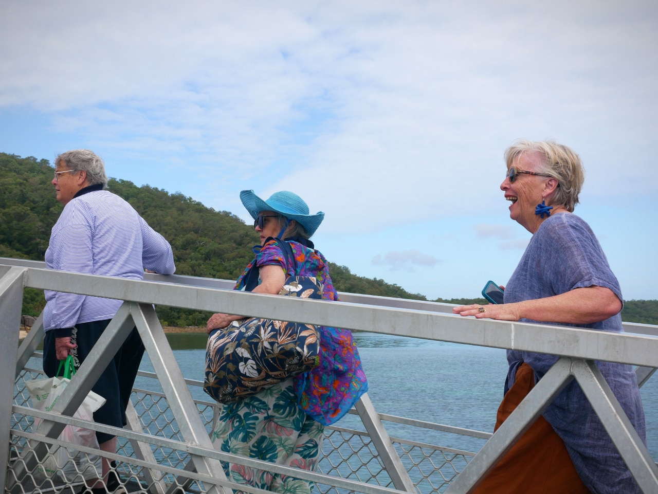 A man followed by two women cross a bridge onto an island